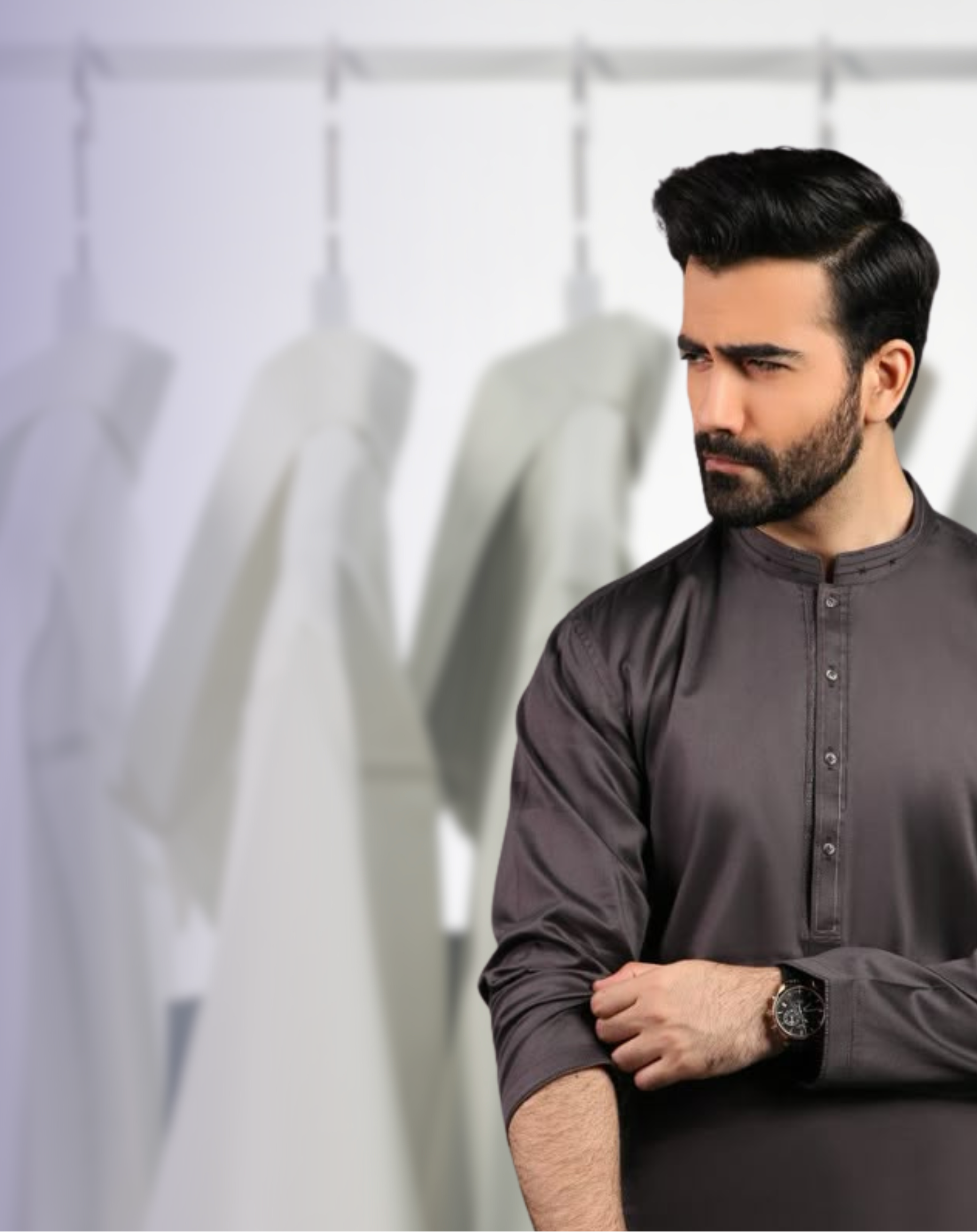 Man wearing a dark gray traditional outfit against a white background