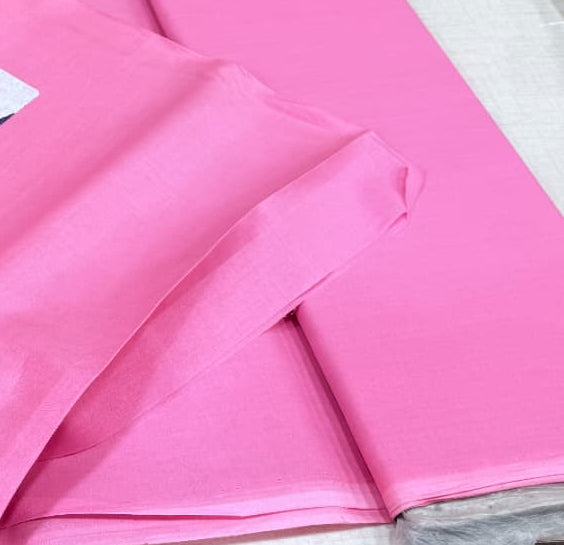 Pink fabric with geometric patterns on a table with other fabrics in the background