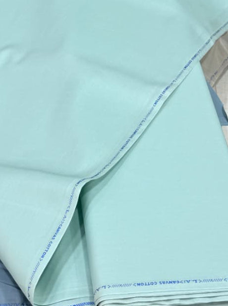 Stack of folded fabric sheets with a light blue sheet on top, surrounded by other colored fabrics.